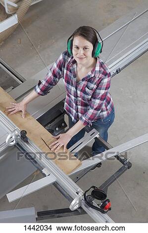 High angle portrait of happy female carpenter using a sliding table saw in workshop View Large Photo Image Picture - High angle portrait of happy female carpenter using a sliding table saw in workshop. Fotosearch