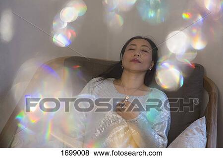 High angle view of crystal decorations hanging over mature woman reclining on sofa at home View Large Photo Image Stock Photo - High angle view of crystal decorations hanging over mature woman reclining on sofa at home. Fotosearch