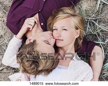 High angle view of man kissing woman while lying on field View Large Photo Image Stock Photography - High angle view of man kissing woman while lying on field. Fotosearch