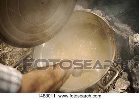 Stock Image - High angle view of man stirring food in pot. Fotosearch