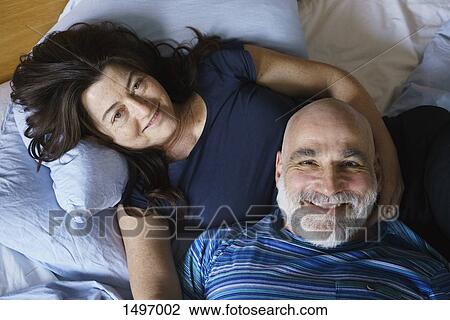 High angle view of mature couple lying on bed at home View Large Photo Image Stock Image - High angle view of mature couple lying on bed at home. Fotosearch