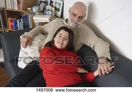 Stock Photo - High angle view of mature couple relaxing on sofa at home. Fotosearch