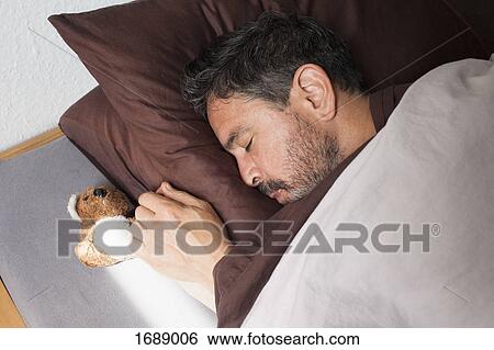 High angle view of mature man sleeping by small teddy bear on bed at home View Large Photo Image Stock Photograph - High angle view of mature man sleeping by small teddy bear on bed at home. Fotosearch
