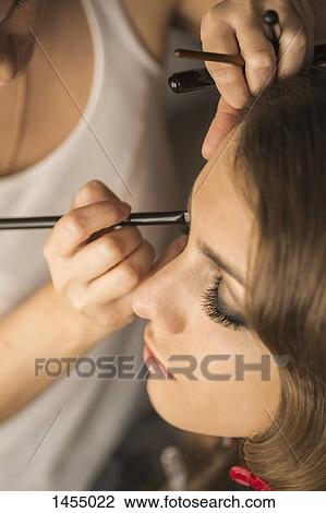 Stock Image - High angle view of woman applying eye make-up on fashion model. Fotosearch