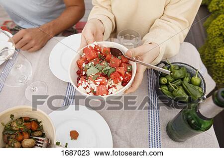 High angle view of woman holding fruit salad bowl at outdoor table while sitting with friend View Large Photo Image Stock Image - High angle view of woman holding fruit salad bowl at outdoor table while sitting with friend. Fotosearch