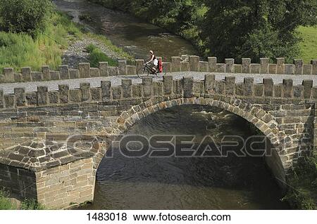 High angle view of woman riding bicycle on bridge View Large Photo Image Stock Photo - High angle view of woman riding bicycle on bridge. Fotosearch