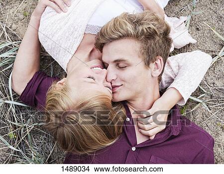 Picture - High angle view of young couple while lying on field. Fotosearch