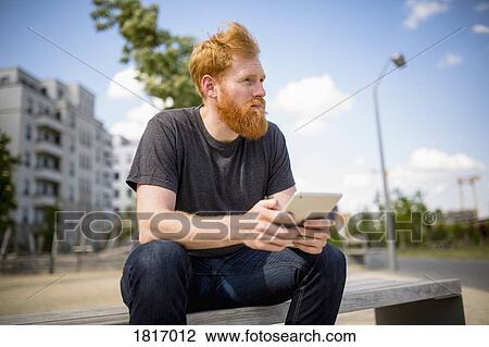 Hipster man with beard using digital tablet on urban bench View Large Photo Image Stock Image - Hipster man with beard using digital tablet on urban bench. Fotosearch