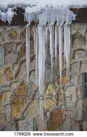 Icicles hanging over stone house roof View Large Photo Image Stock Photo - Icicles hanging over stone house roof. Fotosearch