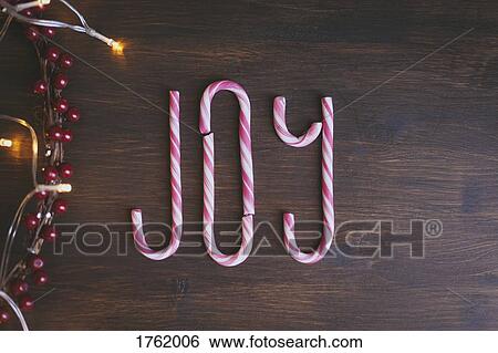 JOY written with candy canes and next to Christmas decorations on wooden background View Large Photo Image Stock Photograph - JOY written with candy canes and next to Christmas decorations on wooden background. Fotosearch