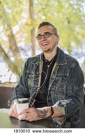 Laughing man drinking coffee and listening to music at cafe View Large Photo Image Stock Image - Laughing man drinking coffee and listening to music at cafe. Fotosearch