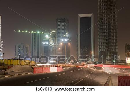 Light trails on illuminated street against cityscape at night View Large Photo Image Stock Image - Light trails on illuminated street against cityscape at night. Fotosearch