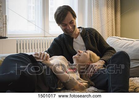 Stock Photo - Loving mature couple looking at each other in living room. Fotosearch