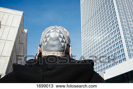 Low angle rear view of man with tattoos and ear plugs against skyscraper in city View Large Photo Image Stock Image - Low angle rear view of man with tattoos and ear plugs against skyscraper in city. Fotosearch