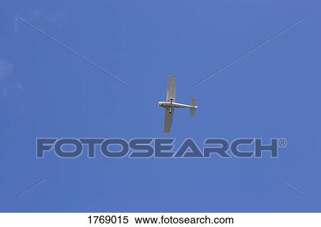 Low angle view airplane flying in sunny blue sky View Large Photo Image Stock Photography - Low angle view airplane flying in sunny blue sky. Fotosearch