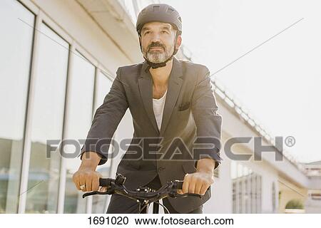 Low angle view of businessman cycling by building on sunny day View Large Photo Image Stock Image - Low angle view of businessman cycling by building on sunny day. Fotosearch
