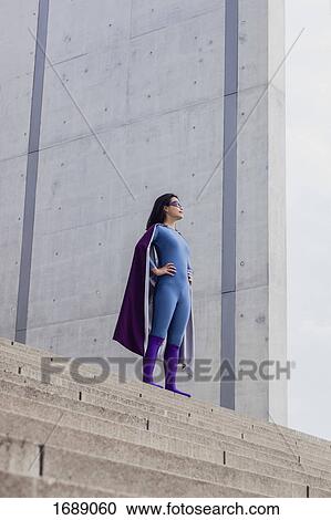 Low angle view of female superhero standing on steps against wall View Large Photo Image Stock Image - Low angle view of female superhero standing on steps against wall. Fotosearch