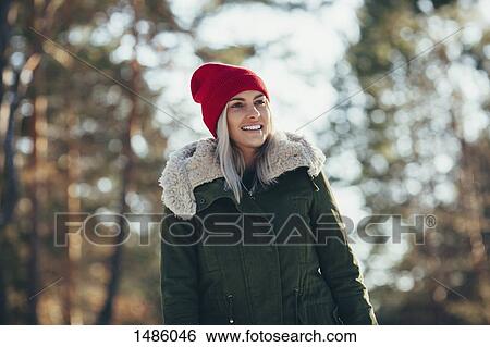 Low angle view of happy young woman wearing knit hat and jacket while looking away View Large Photo Image Stock Photograph - Low angle view of happy young woman wearing knit hat and jacket while looking away. Fotosearch