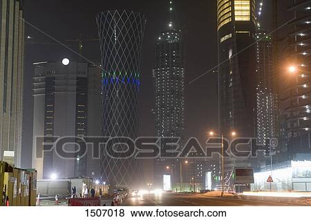 Low angle view of illuminated buildings by street in city at night View Large Photo Image Stock Photo - Low angle view of illuminated buildings by street in city at night. Fotosearch