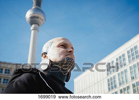 Low angle view of man with tattoos and ear plugs below the TV Tower, Berlin, Germany View Large Photo Image Stock Photo - Low angle view of man with tattoos and ear plugs below the TV Tower, Berlin, Germany. Fotosearch