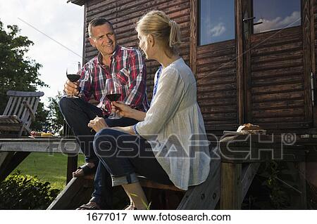 Low angle view of mature couple talking and having wine while resting outside farmhouse View Large Photo Image Stock Photo - Low angle view of mature couple talking and having wine while resting outside farmhouse. Fotosearch