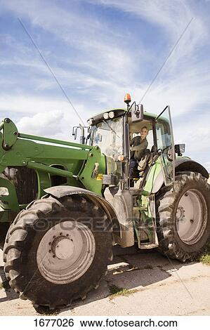 Low angle view of mature woman driving tractor against sky View Large Photo Image Stock Photograph - Low angle view of mature woman driving tractor against sky. Fotosearch