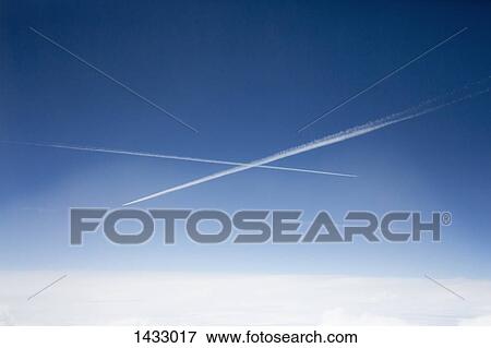 Low angle view of vapor trails in blue sky View Large Photo Image Stock Photo - Low angle view of vapor trails in blue sky. Fotosearch