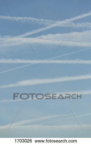Low angle view of vapor trails in blue sky View Large Photo Image Stock Photograph - Low angle view of vapor trails in blue sky. Fotosearch