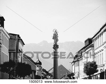 Stock Image - Low angle view of Virgin Mary statue on column amidst buildings and against sky. Fotosearch