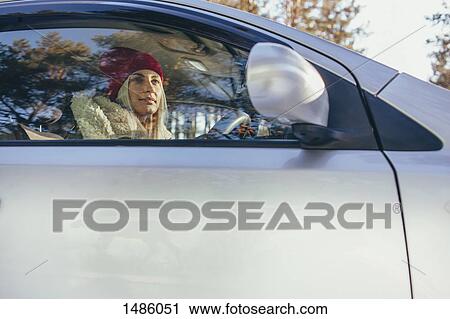 Stock Image - Low angle view of woman driving car during winter. Fotosearch