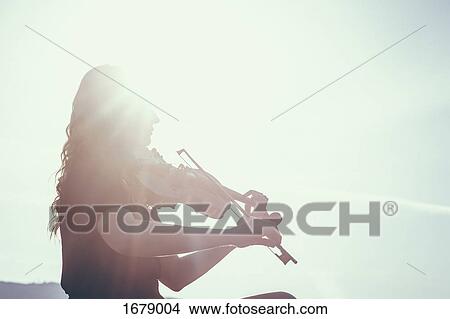 Low angle view of woman playing violin against sky on sunny day View Large Photo Image Picture - Low angle view of woman playing violin against sky on sunny day. Fotosearch