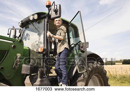 Low angle view of woman standing on tractor at farm against sky during sunny day View Large Photo Image Stock Image - Low angle view of woman standing on tractor at farm against sky during sunny day. Fotosearch