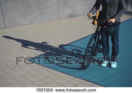 Low section of businessman standing with bicycle on street View Large Photo Image Picture - Low section of businessman standing with bicycle on street. Fotosearch