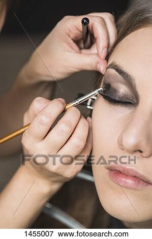 Stock Photo - Make-up artist applying eyeshadow on fashion model. Fotosearch