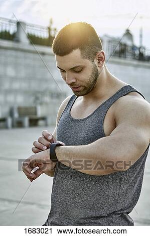 Male athlete using smart watch while standing at footpath View Large Photo Image Stock Image - Male athlete using smart watch while standing at footpath. Fotosearch