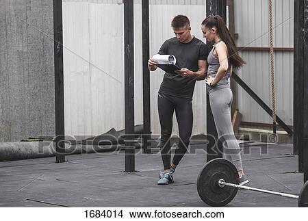 Male coach instructing female athlete over clipboard during crossfit training View Large Photo Image Picture - Male coach instructing female athlete over clipboard during crossfit training. Fotosearch