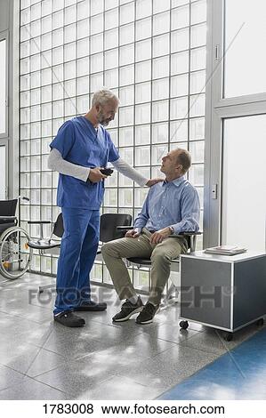 Male doctor talking to, comforting patient in clinic waiting room View Large Photo Image Stock Photo - Male doctor talking to, comforting patient in clinic waiting room. Fotosearch
