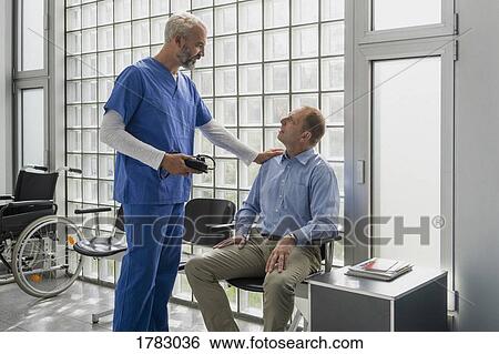 Male doctor talking to, comforting patient in clinic waiting room View Large Photo Image Stock Photograph - Male doctor talking to, comforting patient in clinic waiting room. Fotosearch
