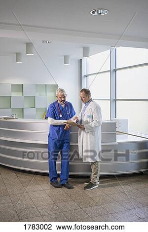 Stock Image - Male doctors discussing medical record in hospital. Fotosearch