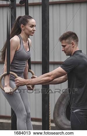 Male instructor assisting female athlete exercising on gymnastic rings during crossfit training View Large Photo Image Stock Image - Male instructor assisting female athlete exercising on gymnastic rings during crossfit training. Fotosearch
