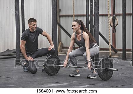 Male instructor looking at female athlete lifting barbell during crossfit training View Large Photo Image Stock Image - Male instructor looking at female athlete lifting barbell during crossfit training. Fotosearch