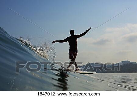 Male surfer balancing on surfboard, riding ocean wave View Large Photo Image Stock Image - Male surfer balancing on surfboard, riding ocean wave. Fotosearch