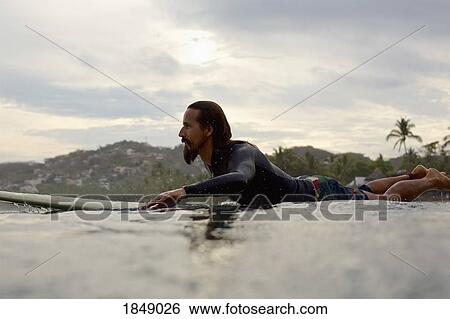 Stock Photograph - Male surfer paddling out on ocean. Fotosearch