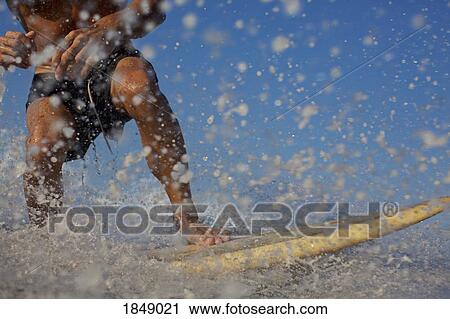 Stock Image - Male surfer riding ocean wave, splashing. Fotosearch