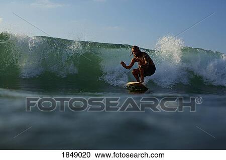 Stock Image - Male surfer riding ocean wave. Fotosearch