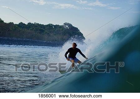 Stock Image - Male surfer riding ocean wave. Fotosearch