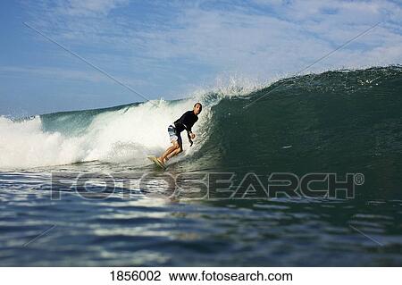 Stock Image - Male surfer riding ocean wave. Fotosearch