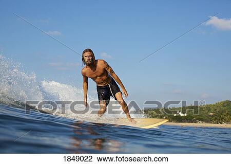 Male surfer riding sunny ocean wave View Large Photo Image Stock Image - Male surfer riding sunny ocean wave. Fotosearch