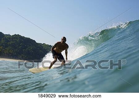 Male surfer riding sunny ocean wave View Large Photo Image Stock Photo - Male surfer riding sunny ocean wave. Fotosearch