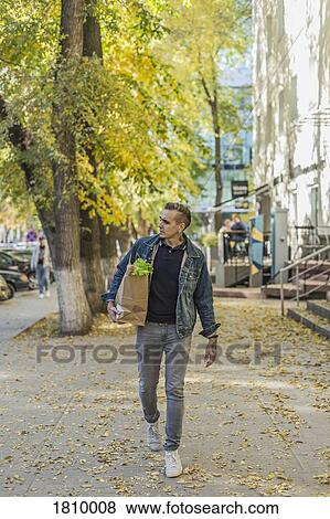 Man carrying groceries on autumn sidewalk View Large Photo Image Stock Photo - Man carrying groceries on autumn sidewalk. Fotosearch
